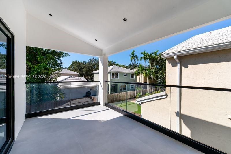 Covered balcony featuring large-format tile flooring, recessed lighting, and a frameless glass railing with a matte black metal frame