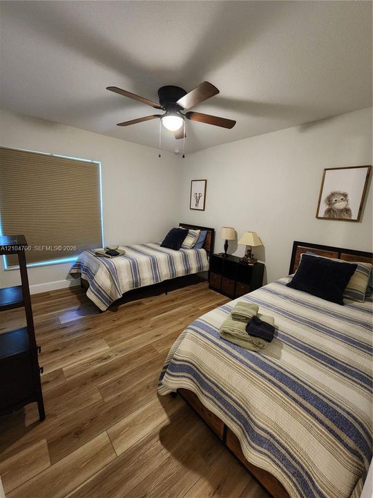 Recessed window with horizontal blinds, wood-finish flooring, and a ceiling fan with integrated lighting