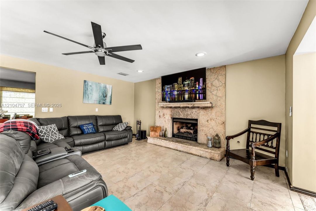 Kitchen featuring extensive wood cabinetry, large central island with stone-finish countertops, stainless steel double wall ovens, built-in coffee station, and tile flooring