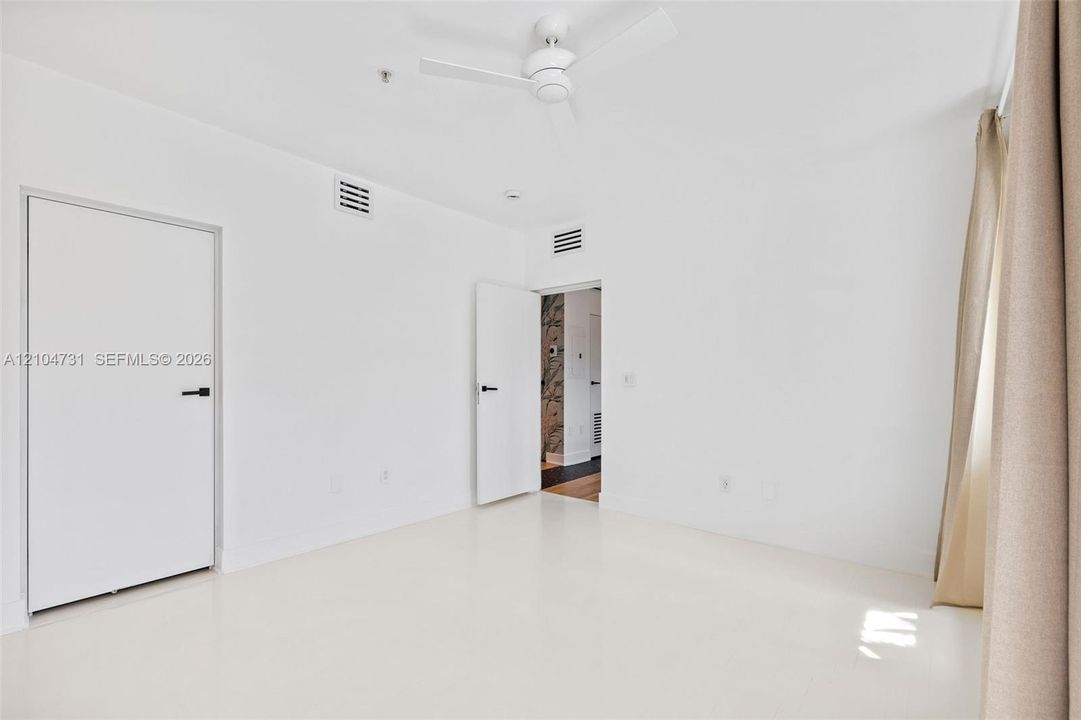 Recessed lighting, smooth white walls, and a ceiling fan