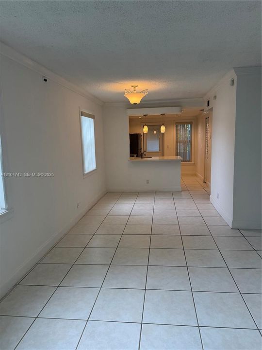 Tile flooring, crown molding, wall-mounted light fixture, pass-through window to kitchen, built-in kitchen cabinetry