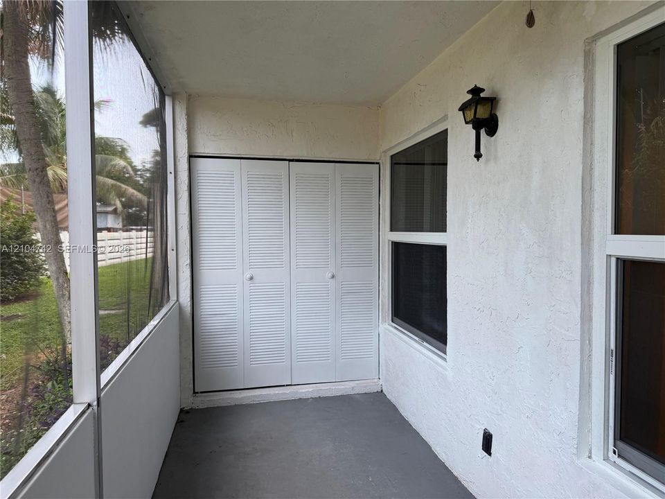 Screened patio featuring white louvered bifold doors, stucco exterior, and wall-mounted exterior lighting