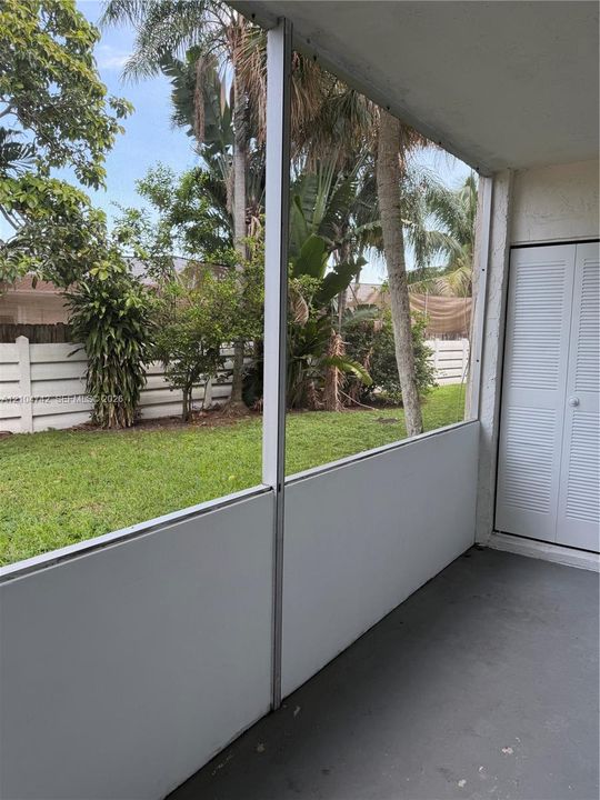 Screened outdoor living area featuring a concrete floor, louvered exterior door, and partial privacy wall