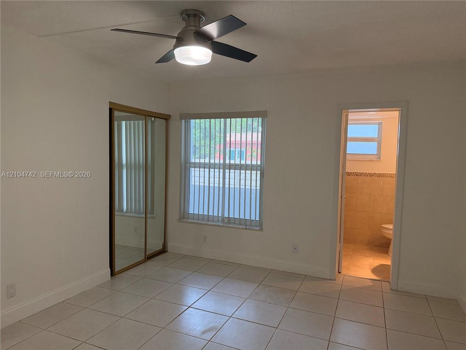 White tile flooring, a window with vertical blinds, a ceiling fan with integrated lighting, and mirrored sliding closet doors