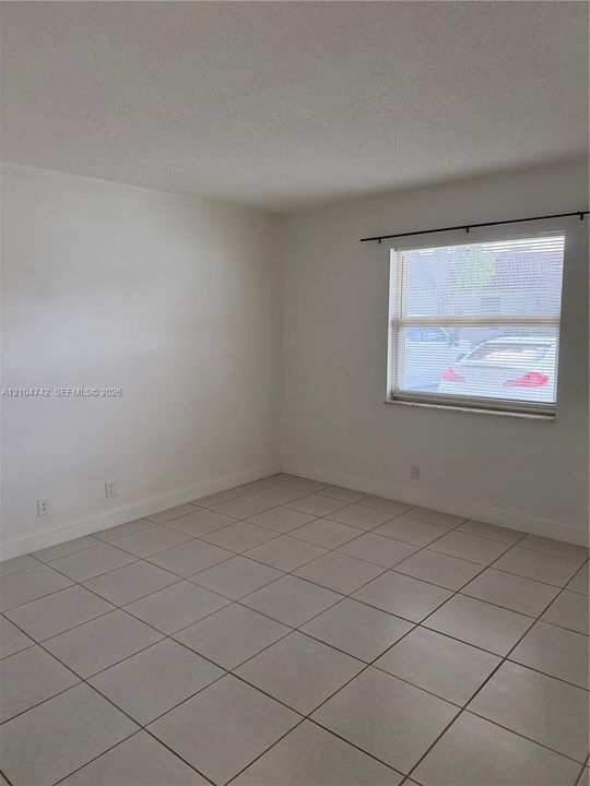 White tile flooring with dark grout, white walls, and a window with horizontal blinds
