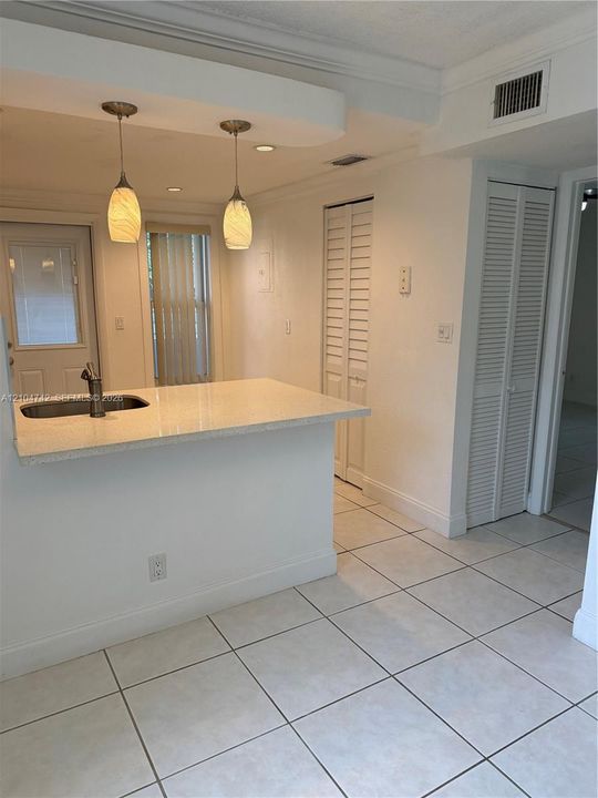 Island with integrated sink, dual pendant lighting, and tiled flooring