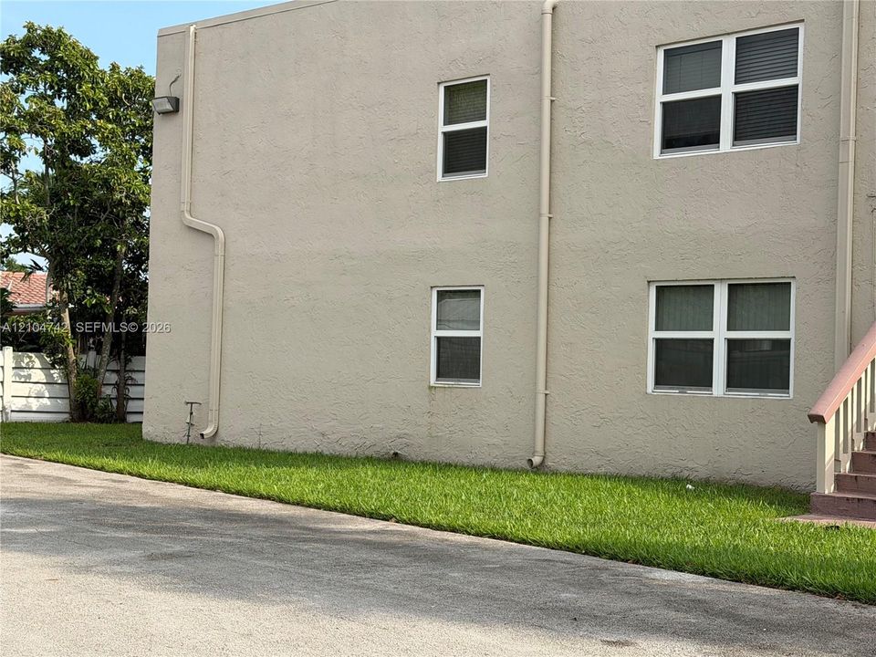 Stucco exterior with multiple windows, exterior lighting fixture, and a partial outdoor staircase