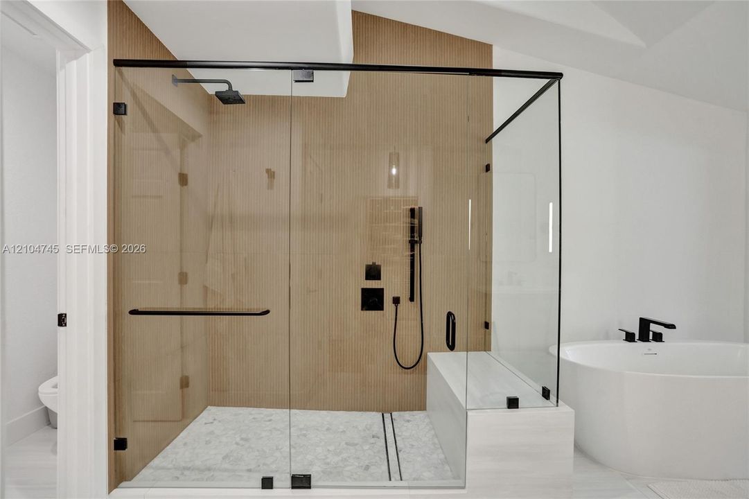 Glass-enclosed shower with a built-in bench, matte black fixtures, and a rain showerhead