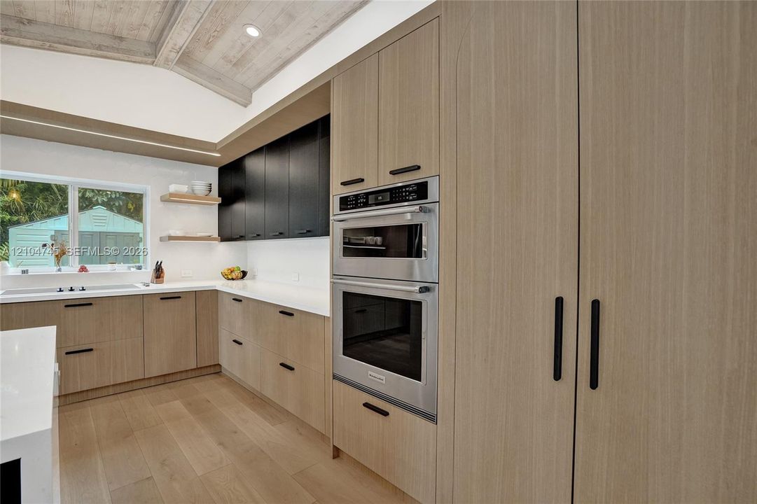 Kitchen featuring a vaulted wood-paneled ceiling, integrated stainless steel appliances, light wood-finish cabinetry, white countertops, and wood-finish flooring