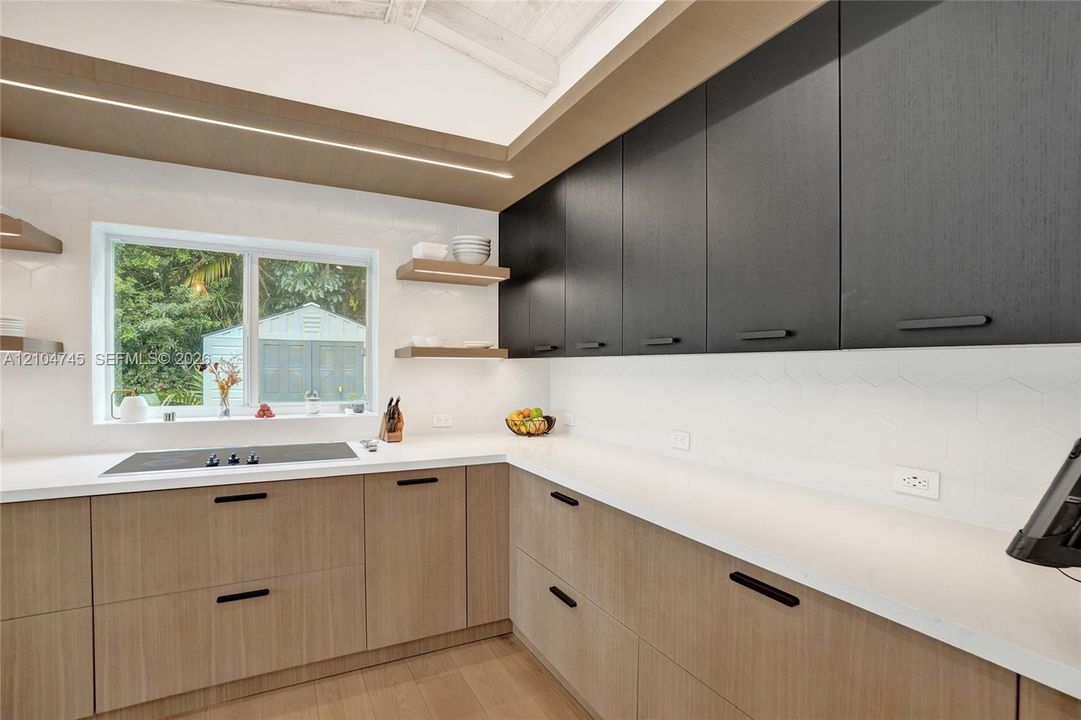 Modern kitchen featuring wood-finish lower cabinetry, dark-finish upper cabinetry, white countertops, and a white hexagonal tile backsplash