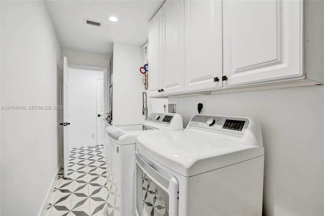 White shaker cabinetry, recessed lighting, and patterned floor tiling