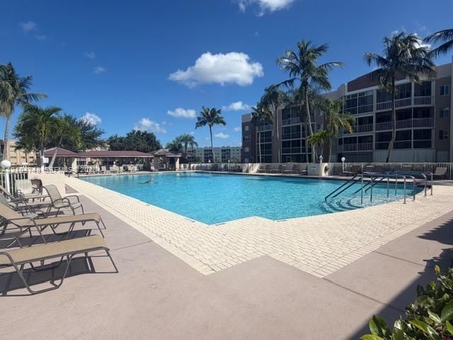 Expansive outdoor pool with integrated steps, surrounded by a paved deck and a separate covered gazebo structure