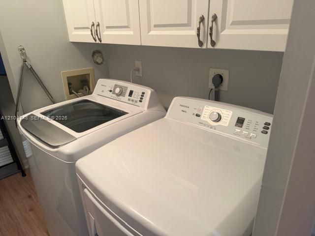 White shaker-style cabinetry with bronze hardware, light gray wall paint, and wood-finish flooring