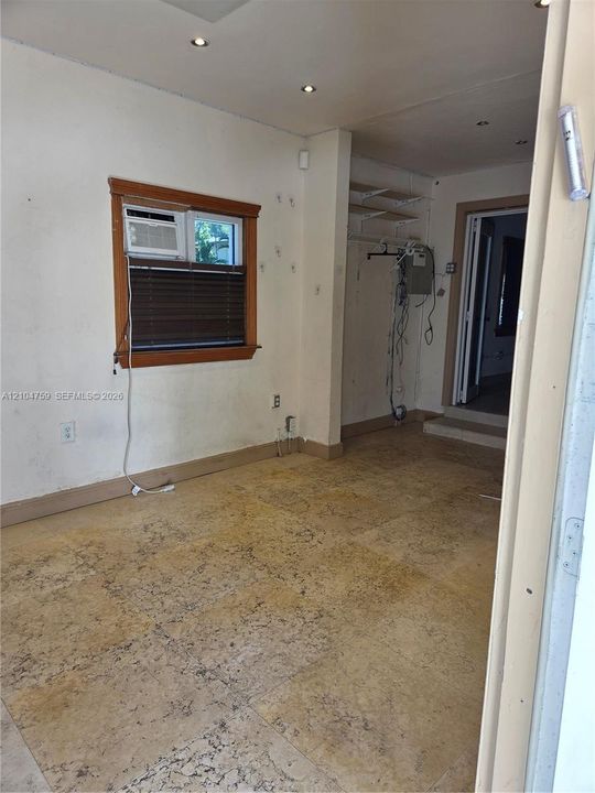Interior space featuring stone-style tile flooring, recessed ceiling lighting, and a window with wood-trim casing