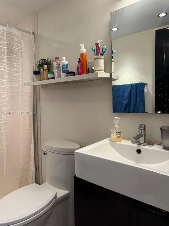 White rectangular vessel sink with a single-handle chrome faucet, black vanity cabinet, and wall-mounted mirror
