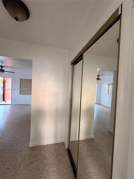 Mirrored sliding closet doors, ceiling-mounted light fixture, and terrazzo flooring