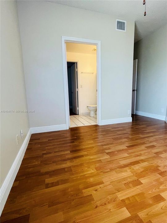 Wood-finish flooring throughout, neutral wall tones, and tiled bathroom flooring