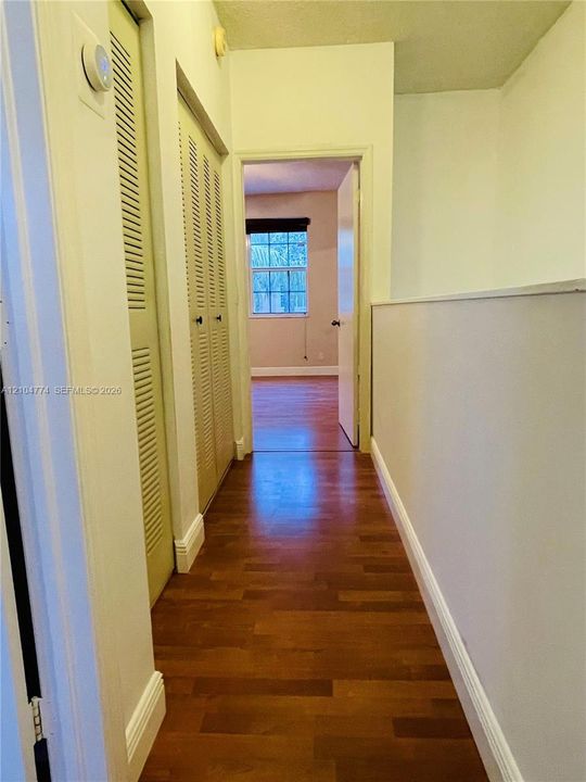 Hallway featuring wood-finish flooring, louvered bi-fold closet doors, and a half-wall partition
