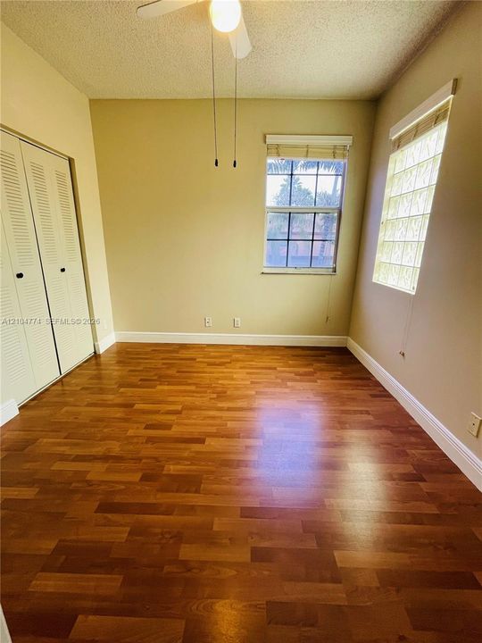 Room featuring wood-finish flooring, a glass block window, a dual-panel window with muntins, and built-in closet storage with louvered doors