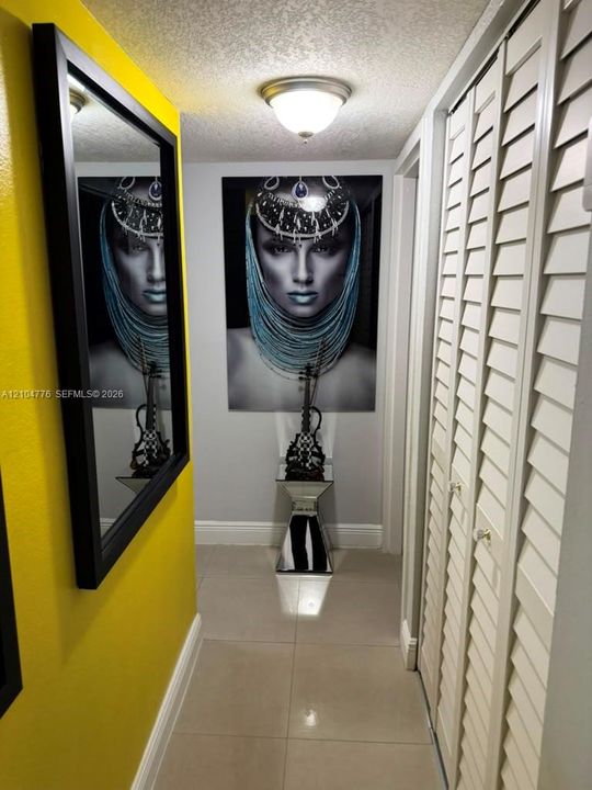 Hallway featuring tile flooring, white baseboards, and louvered bi-fold doors