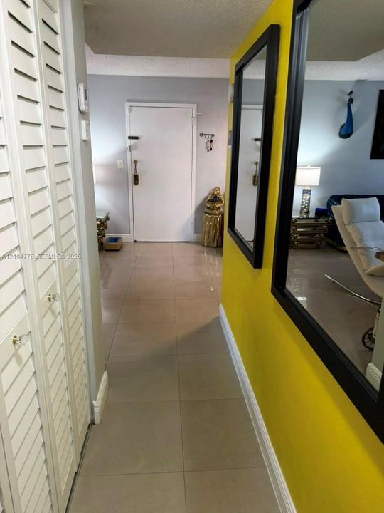 Tile flooring, louvered closet doors with crystal knobs, and a vibrant accent wall with framed mirrors