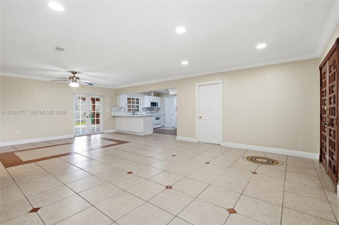 Spacious room featuring tile flooring with decorative inlays, recessed lighting, and a ceiling fan