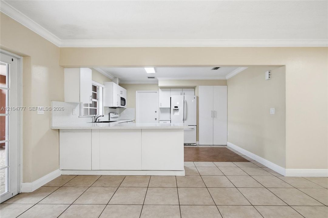 Kitchen with white cabinetry, stainless steel appliances, and a pass-through window