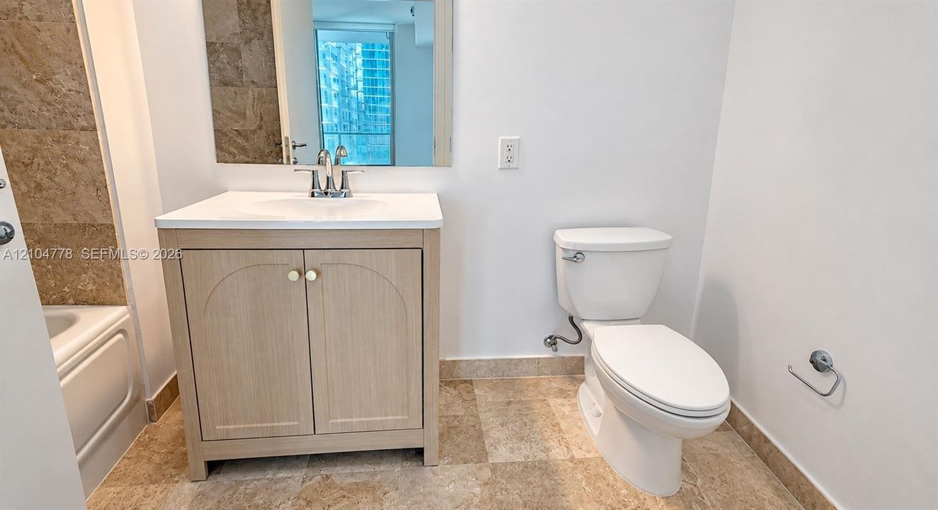 Bathroom featuring a light wood-finish vanity with an integrated sink, polished chrome faucet, and a wall-mounted mirror