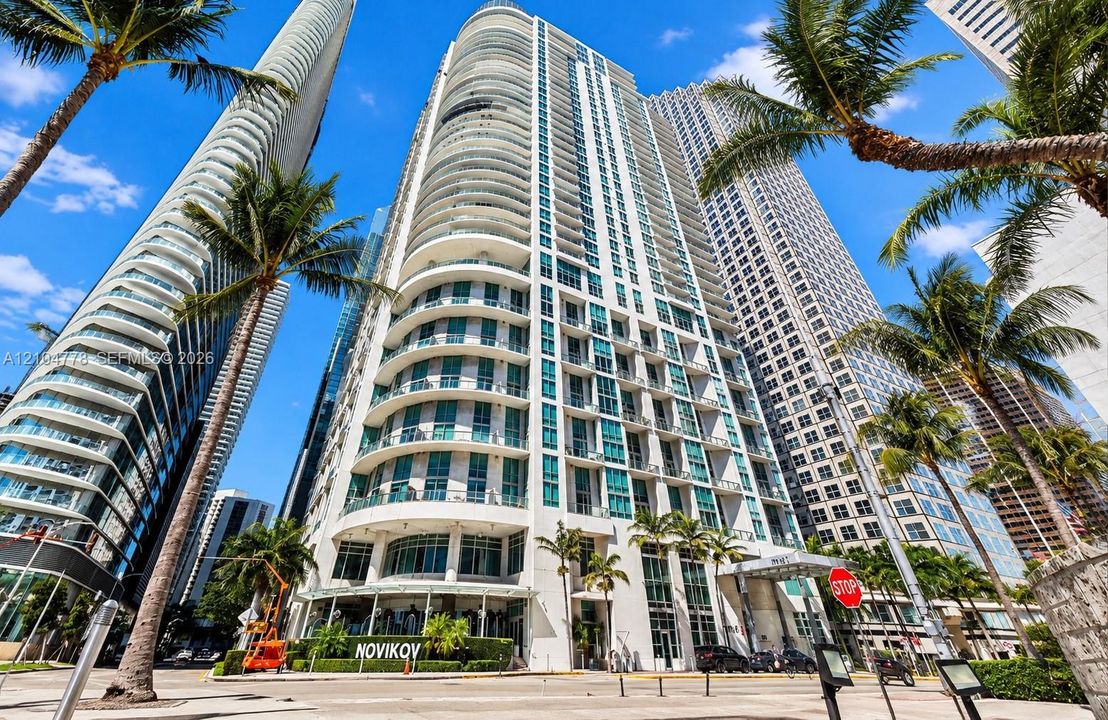 Modern high-rise architecture with curved balconies, floor-to-ceiling windows, and a prominent ground-floor retail space