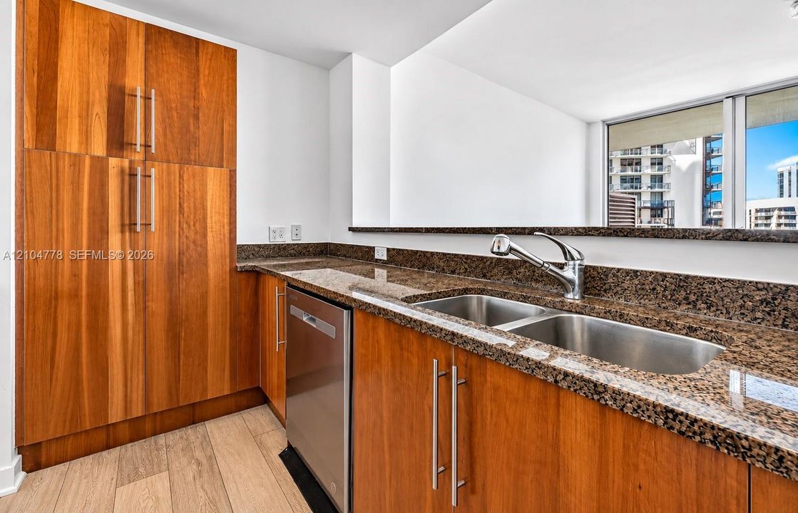 Wood-finish cabinetry and built-in pantry with stainless-steel hardware