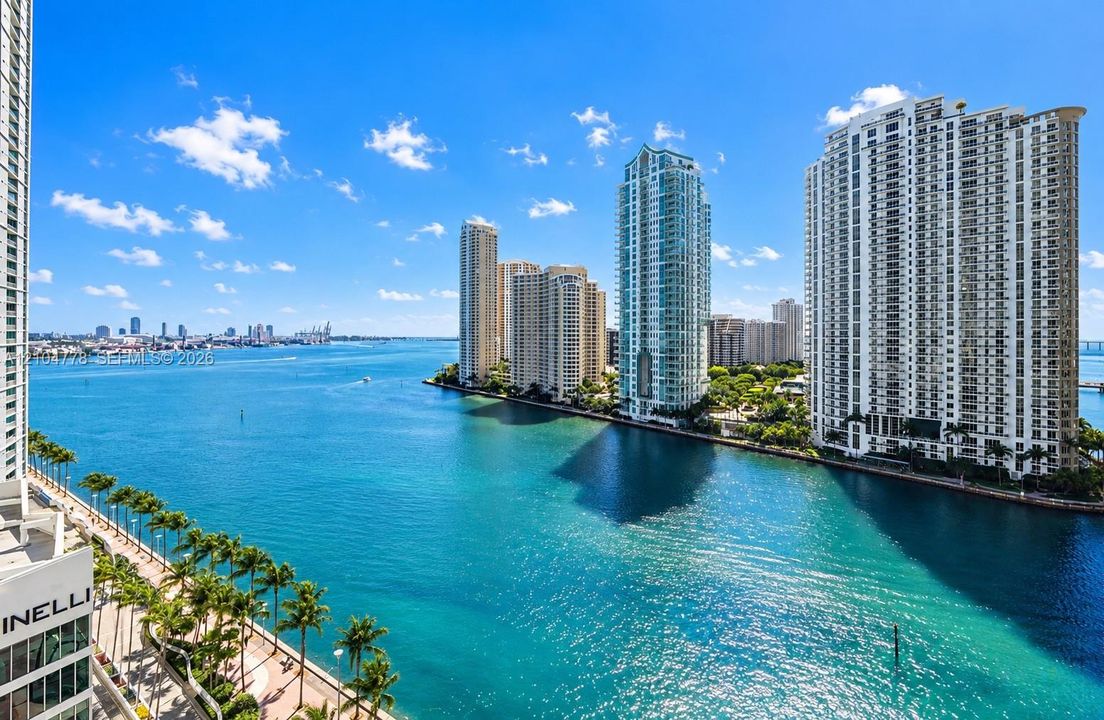 Waterfront property featuring multiple high-rise buildings, an urban skyline, and a palm-lined promenade