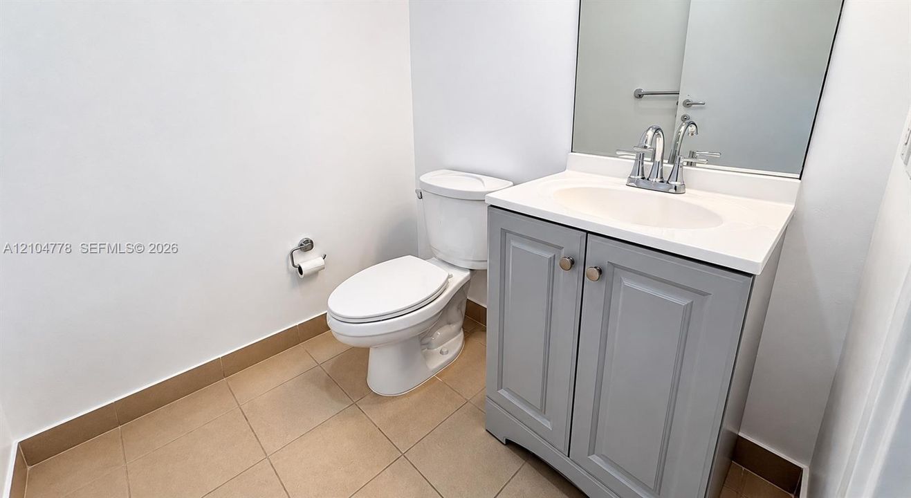White vanity with a rectangular sink, chrome faucet, and integrated mirror