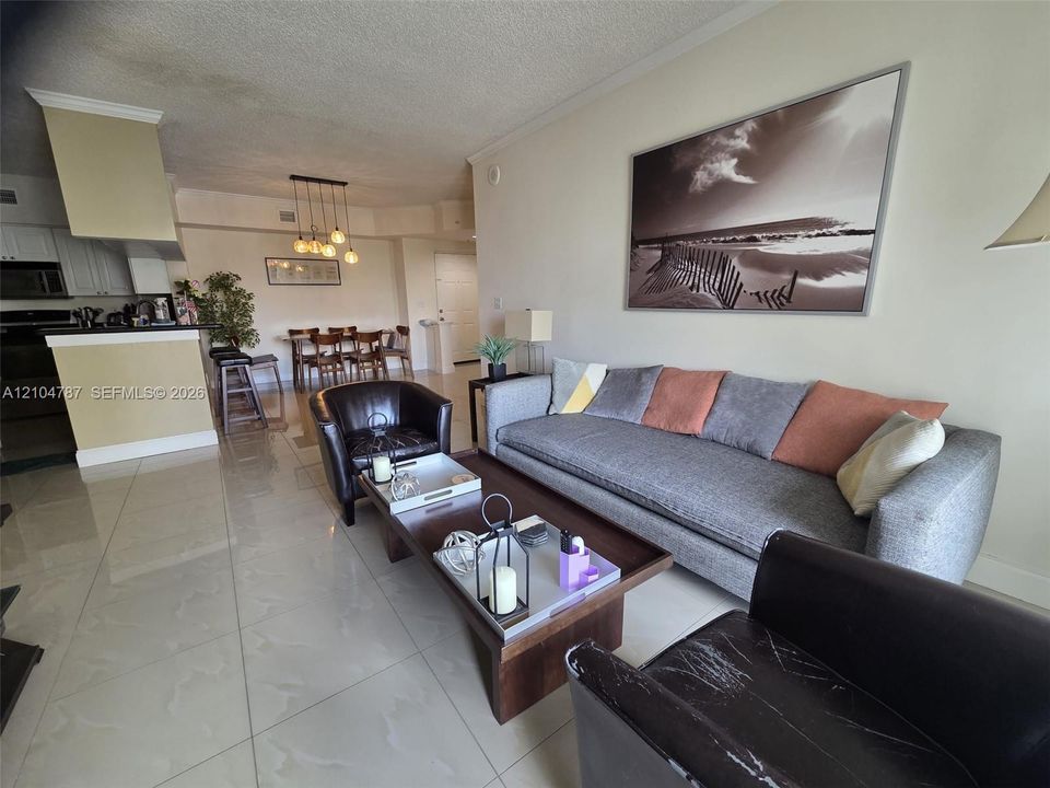 Open-concept interior featuring large-format tile flooring, recessed lighting, and a kitchen peninsula with a breakfast bar