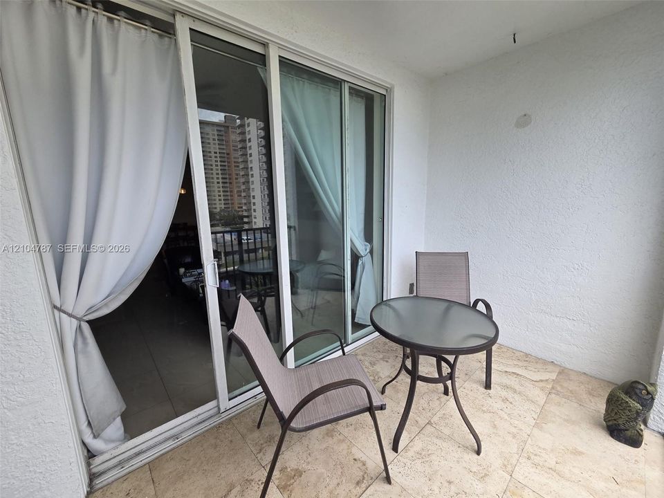 Private covered balcony featuring stone flooring and large sliding glass door entry