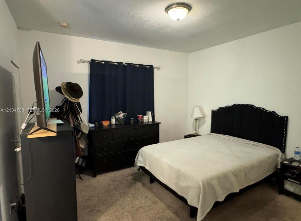 Bedroom with neutral wall paint, carpeted flooring, and a flush-mount ceiling light fixture