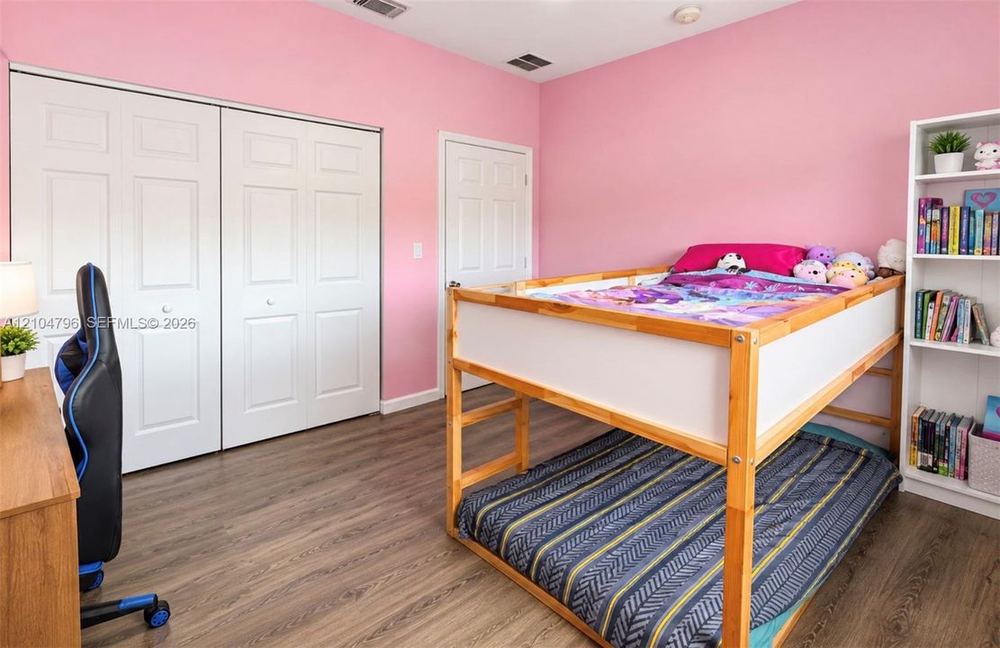 Room featuring wood-finish flooring, dual-panel closet doors, a traditional interior door, and white millwork