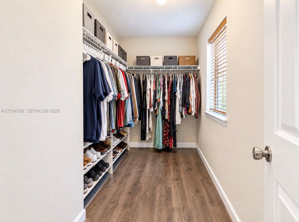 Walk-in closet featuring wood-finish flooring, built-in wire shelving, and a window with blinds