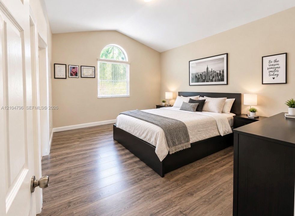 Room featuring vaulted ceilings, wood-finish flooring, and an arched window