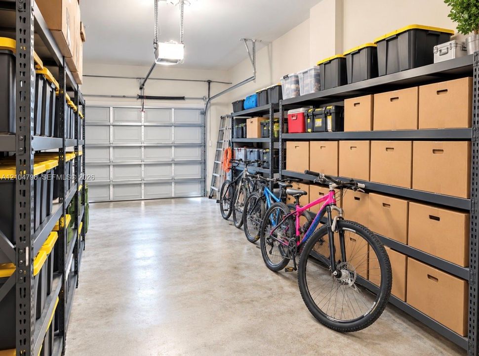Garage space featuring finished concrete flooring, a sectional overhead garage door, and extensive industrial-style metal storage shelving