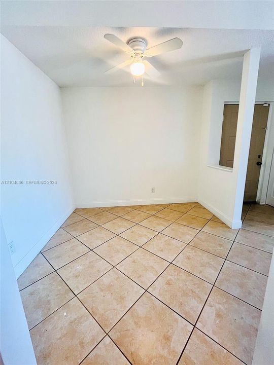 Light-toned tile flooring, white walls, and a ceiling fan with integrated lighting