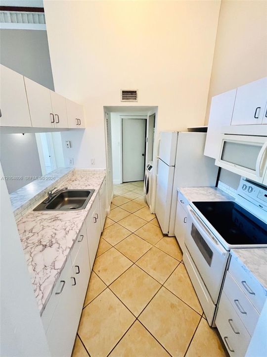 Kitchen featuring diagonal tile flooring, white cabinetry, a stainless steel sink, and light-colored countertops