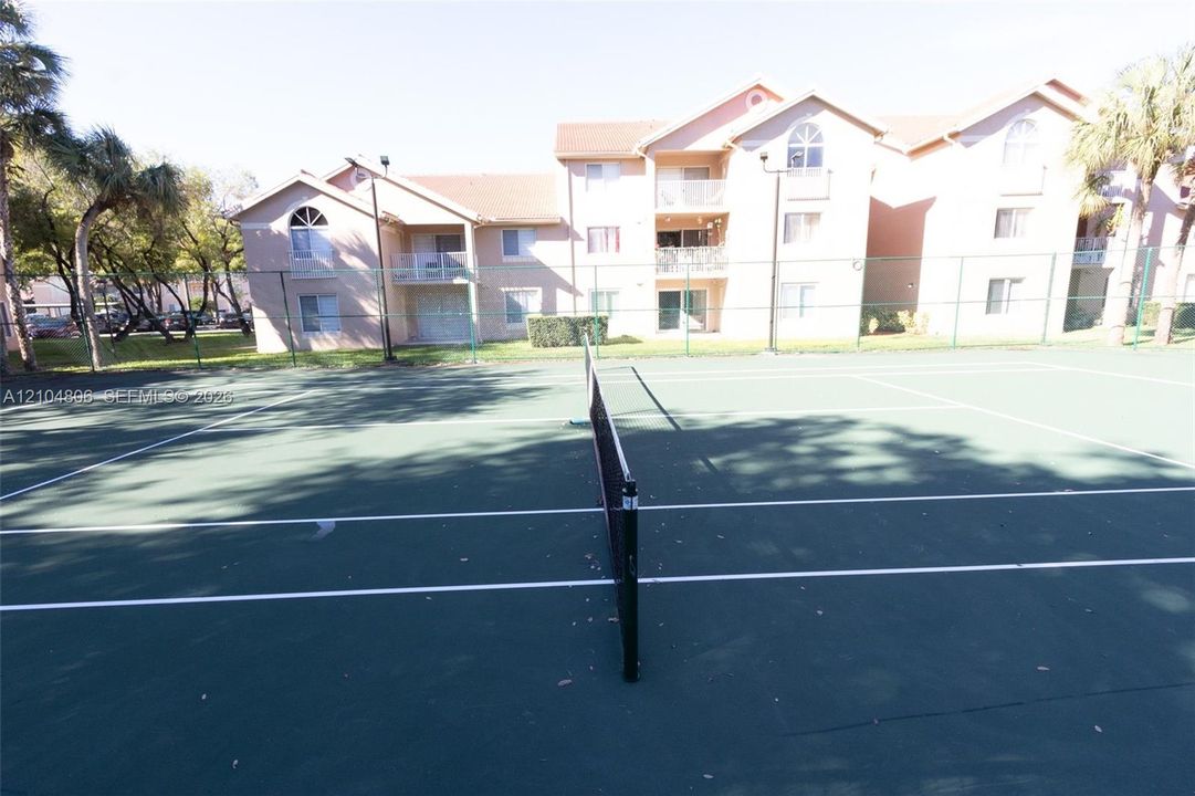 Tennis court featuring a green playing surface and white court lines
