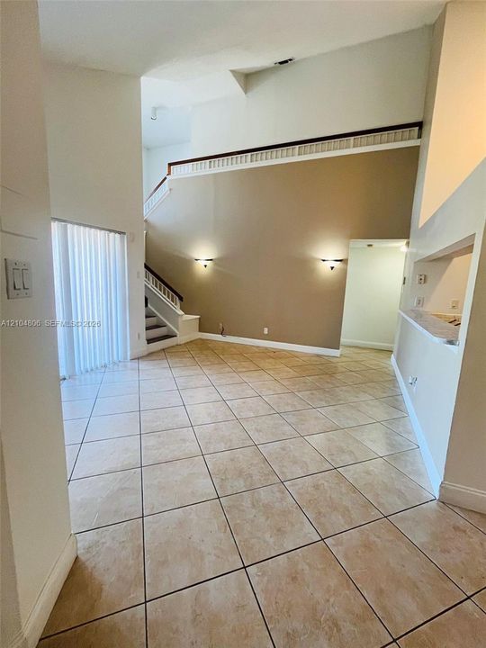 High ceilings, neutral-toned walls, tile flooring, two-story architectural elements, and recessed wall lighting