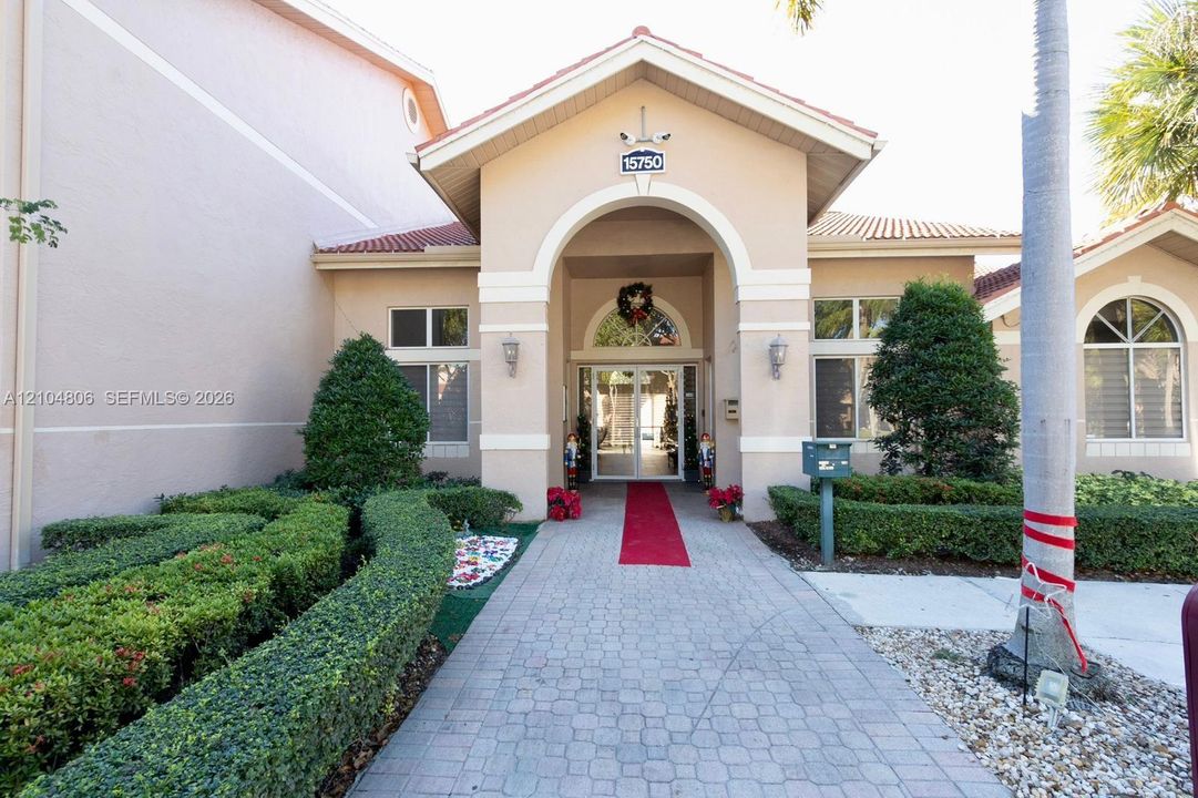 Stucco exterior with a tiled roof, arched entryway, and decorative exterior lighting