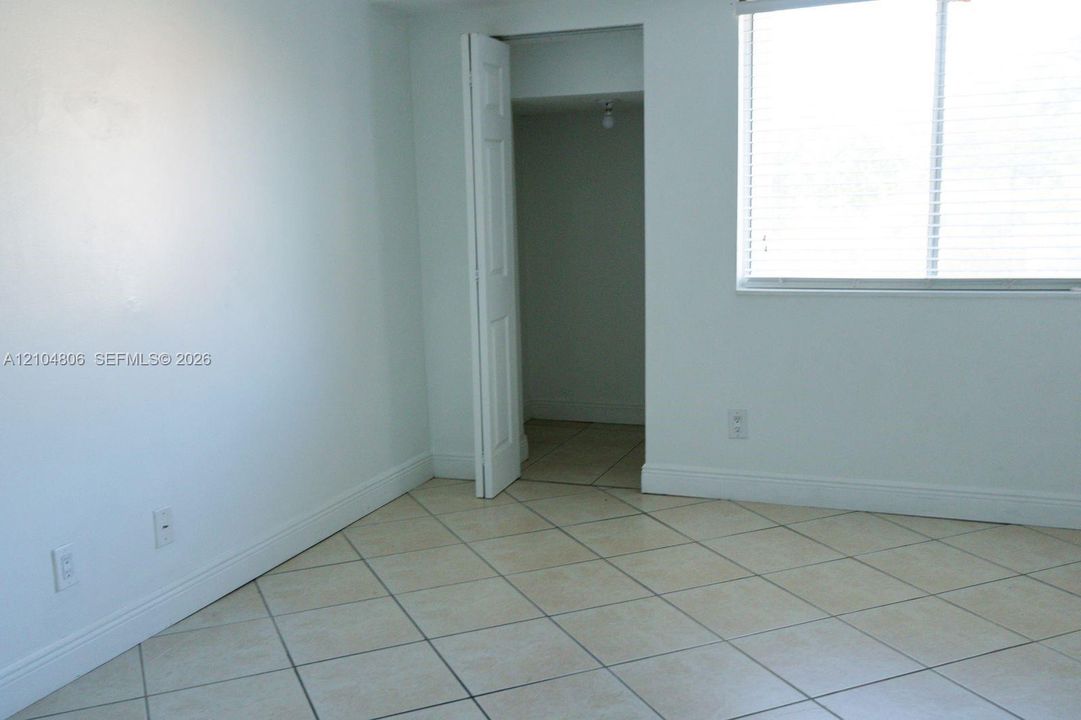 Neutral-toned tile flooring, white walls, and a window with blinds