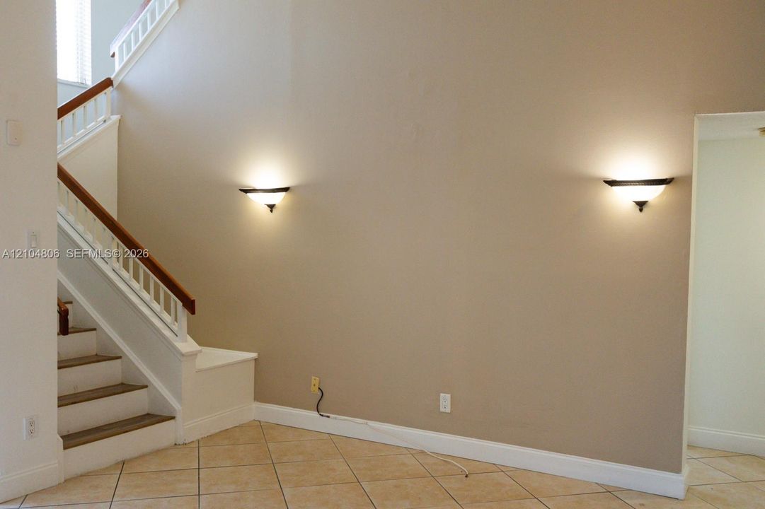 Staircase with wood handrail, white balusters, and painted risers