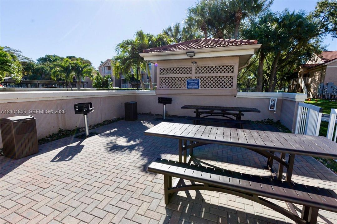 Paver patio featuring multiple picnic tables and a covered BBQ area