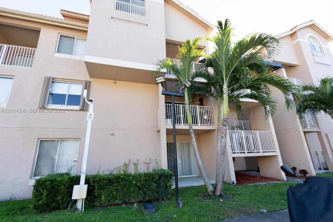 Multi-story building exterior with individual balconies, architectural roofline, and established palm trees