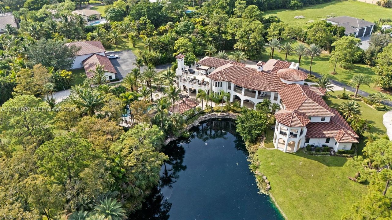 Expansive property featuring a multi-level structure with a tile roof, extensive landscaping, and a substantial water feature