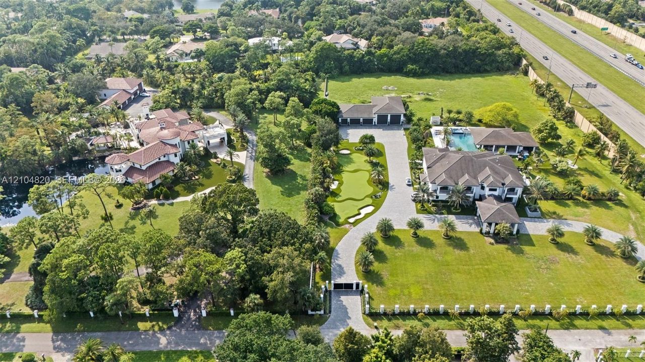 Expansive property featuring two distinct residences, a private putting green, a swimming pool, and a gated entry